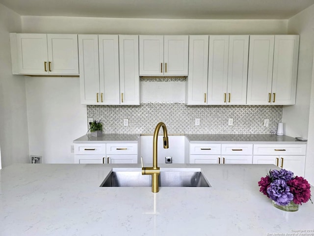 911 Florida, San Antonio, TX 78210 - kitchen featuring a sink, light stone countertops, decorative backsplash, and white cabinetry