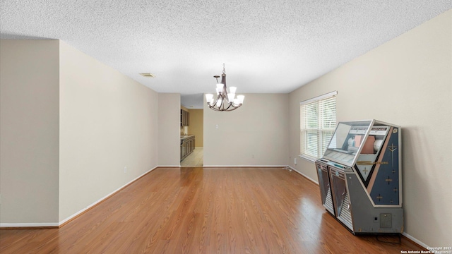 4714 Irish Elm, San Antonio, TX 78247 - unfurnished room featuring a chandelier, light wood-style flooring, a textured ceiling, and baseboards
