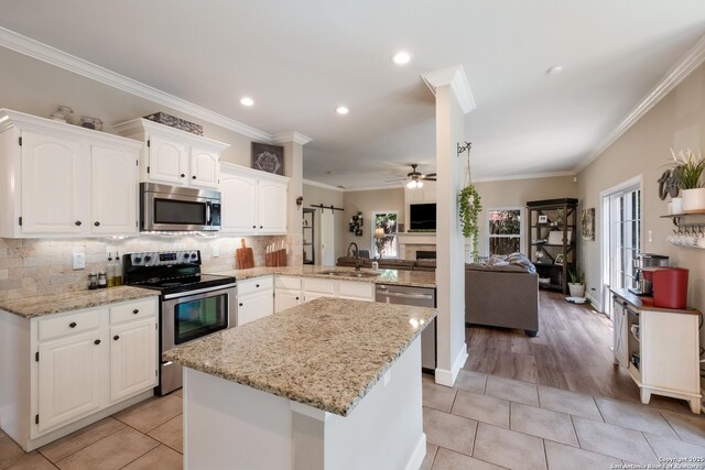 13314 Galicia, Universal City, TX 78148 - kitchen featuring appliances with stainless steel finishes, open floor plan, a peninsula, a ceiling fan, and crown molding