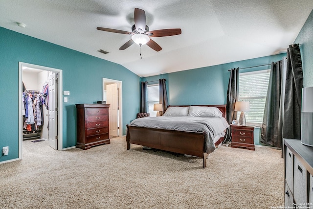 7719 Proton Smt, San Antonio, TX 78252 - bedroom featuring lofted ceiling, a walk in closet, carpet flooring, a textured ceiling, and a ceiling fan