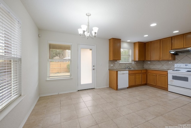 6015 Wisteria Hl, San Antonio, TX 78218 - kitchen featuring white appliances, under cabinet range hood, backsplash, a chandelier, and brown cabinets