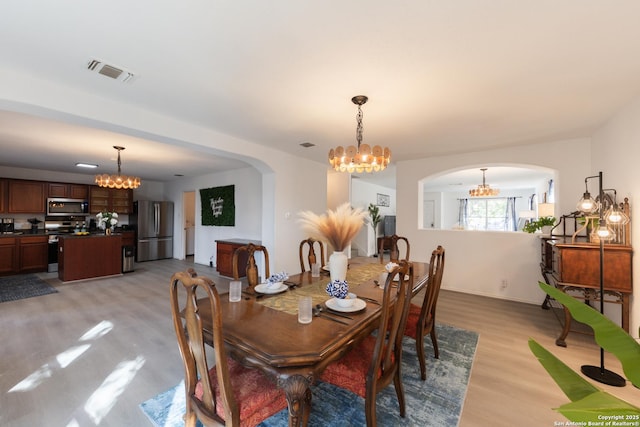 10819 Indigo, San Antonio, TX 78239 - dining space with a chandelier, arched walkways, and light wood-style floors