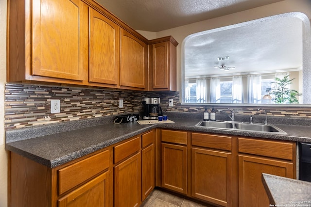 11610 Lemonmint, San Antonio, TX 78245 - kitchen featuring a sink, backsplash, brown cabinetry, dark countertops, and light tile patterned floors
