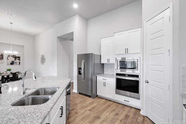 513 Foxbrook, Cibolo, TX 78108 - kitchen featuring stainless steel appliances, a sink, light wood finished floors, a chandelier, and white cabinets