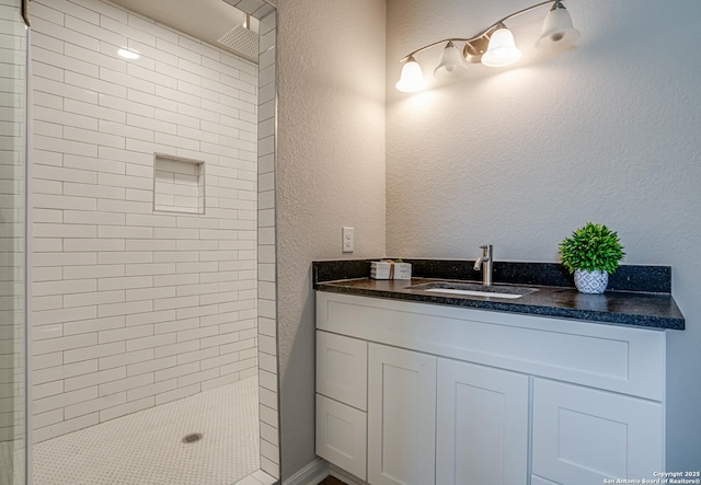 2411 W Huisache Ave, San Antonio, TX 78228 - full bath with a tile shower, a textured wall, and vanity