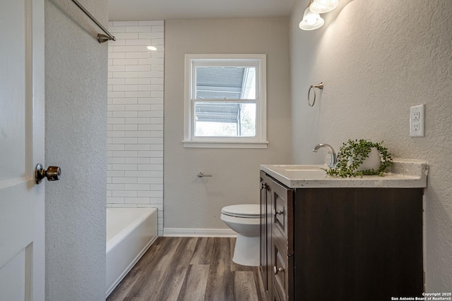 2411 W Huisache Ave, San Antonio, TX 78228 - bathroom with wood finished floors, toilet, vanity, a textured wall, and baseboards
