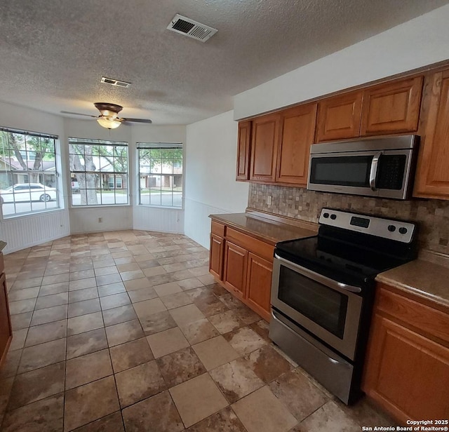 3730 Candlestone, San Antonio, TX 78244 - kitchen with appliances with stainless steel finishes, decorative backsplash, a textured ceiling, a ceiling fan, and brown cabinets