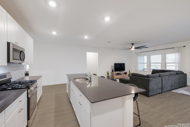 5957 Cerulean, Bulverde, TX 78163 - kitchen with appliances with stainless steel finishes, a sink, dark countertops, light wood finished floors, and a kitchen breakfast bar