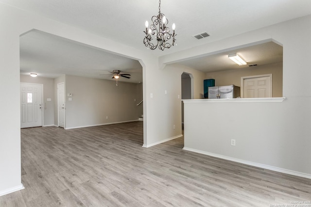 16311 Kentucky Rdg, Selma, TX 78154 - unfurnished living room featuring a ceiling fan, wood finished floors, baseboards, arched walkways, and a chandelier