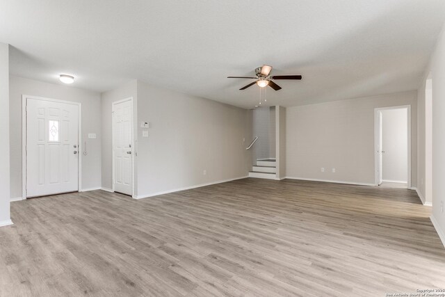 16311 Kentucky Rdg, Selma, TX 78154 - unfurnished living room featuring ceiling fan, light wood finished floors, stairs, and baseboards