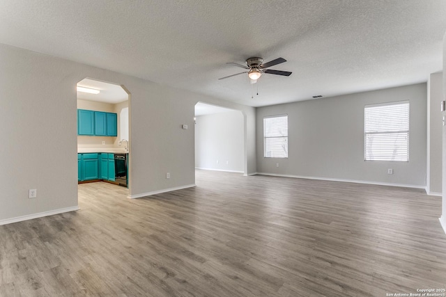 16311 Kentucky Rdg, Selma, TX 78154 - unfurnished room with a ceiling fan, light wood-style floors, arched walkways, a textured ceiling, and baseboards