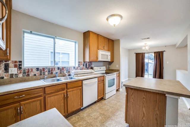 9843 Barhill Bay, San Antonio, TX 78245 - kitchen with white appliances, a sink, brown cabinets, and tasteful backsplash