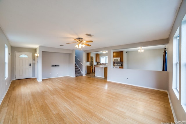 9843 Barhill Bay, San Antonio, TX 78245 - unfurnished living room with stairs, plenty of natural light, light wood-type flooring, and baseboards