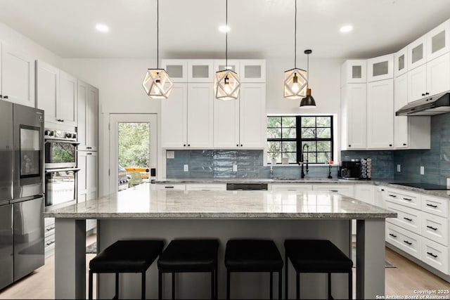 3719 Summer Breeze, San Antonio, TX 78253 - kitchen with appliances with stainless steel finishes, backsplash, a kitchen bar, under cabinet range hood, and recessed lighting