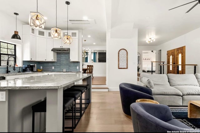 3719 Summer Breeze, San Antonio, TX 78253 - kitchen featuring open floor plan, under cabinet range hood, light wood-style floors, backsplash, and a sink