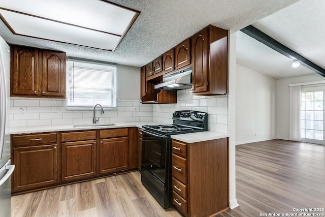 6419 Ridge Tree, San Antonio, TX 78233 - kitchen with under cabinet range hood, a sink, black electric range oven, a textured ceiling, and light wood-type flooring