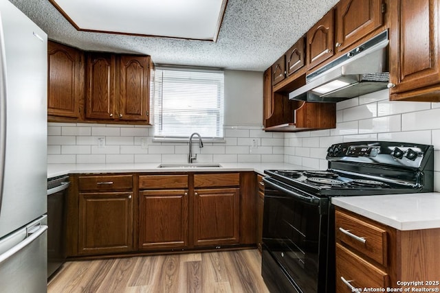 6419 Ridge Tree, San Antonio, TX 78233 - kitchen featuring black range with electric stovetop, freestanding refrigerator, under cabinet range hood, a sink, and light countertops