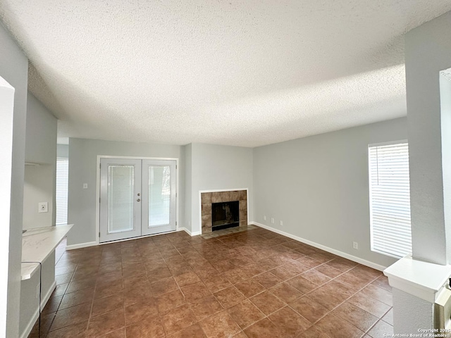 11311 Sir Winston Unit 607, San Antonio, TX 78216 - unfurnished living room with a textured ceiling, a fireplace, baseboards, french doors, and dark tile patterned flooring