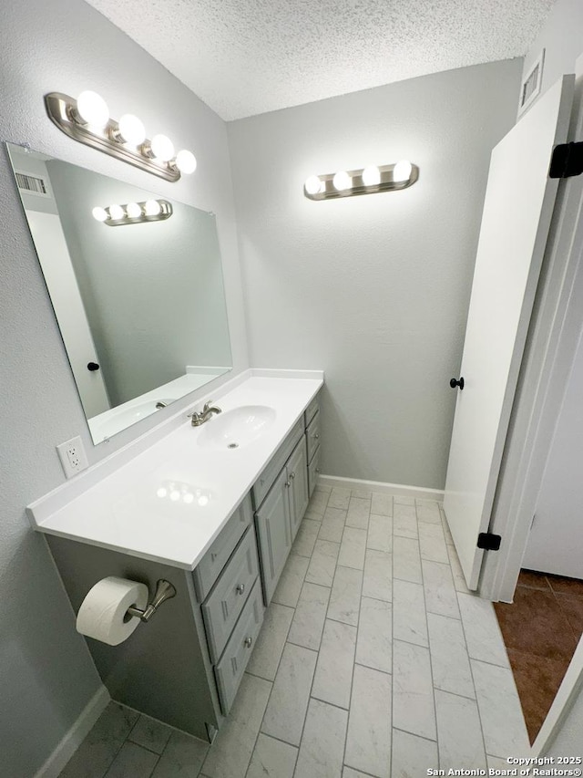 11311 Sir Winston Unit 607, San Antonio, TX 78216 - bathroom featuring a textured ceiling, vanity, and marble finish floors