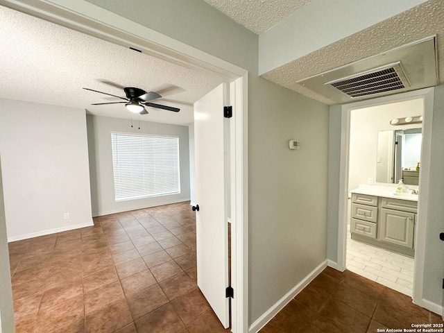 11311 Sir Winston Unit 607, San Antonio, TX 78216 - hallway with a textured ceiling, tile patterned floors, baseboards, and a sink