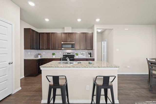 2429 Marty Way, Seguin, TX 78155 - kitchen featuring appliances with stainless steel finishes, an island with sink, a sink, dark brown cabinetry, and a breakfast bar