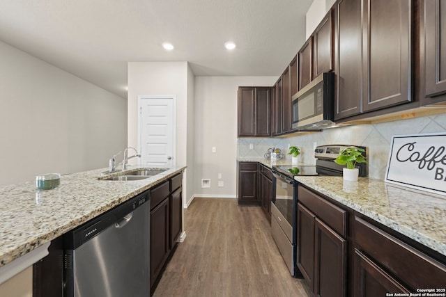 2429 Marty Way, Seguin, TX 78155 - kitchen featuring appliances with stainless steel finishes, a sink, dark brown cabinets, wood finished floors, and tasteful backsplash