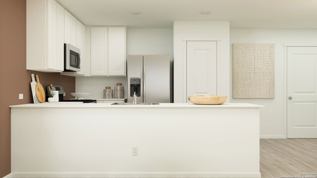 463 Agave Cir, Jourdanton, TX 78026 - kitchen with stainless steel appliances, a peninsula, light wood-style floors, white cabinets, and light countertops