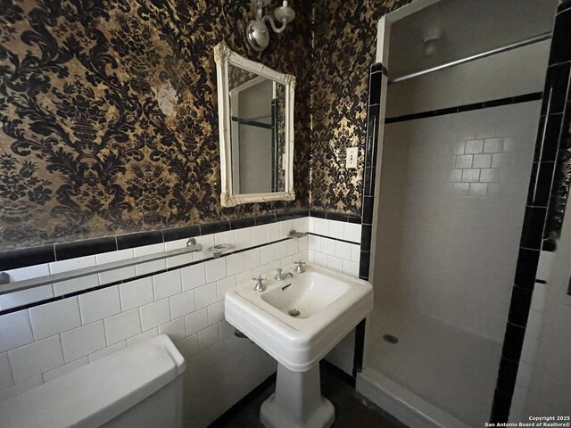 8439 Gardner, San Antonio, TX 78263 - full bath with wallpapered walls, a shower stall, a wainscoted wall, toilet, and tile walls