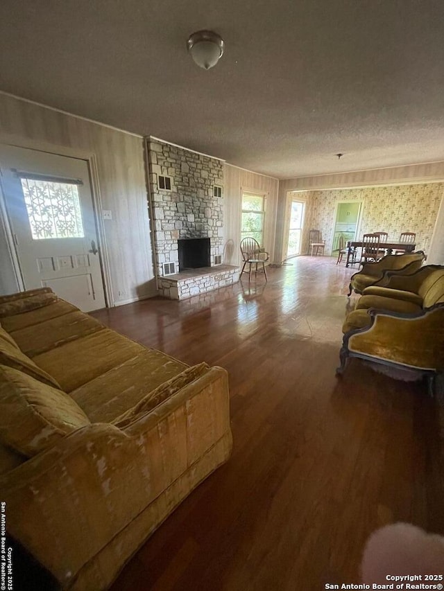 8439 Gardner, San Antonio, TX 78263 - living area with wood finished floors, a stone fireplace, and a textured ceiling