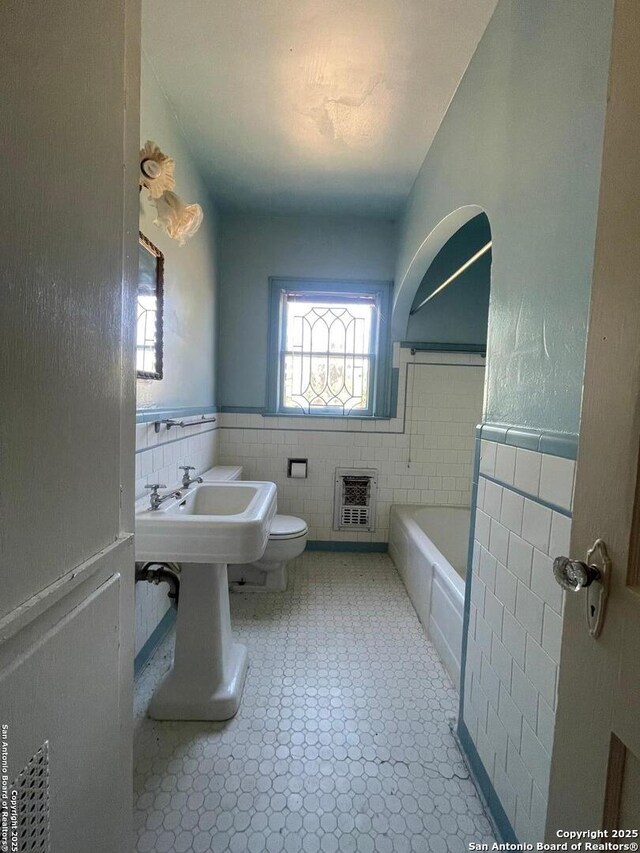 8439 Gardner, San Antonio, TX 78263 - full bathroom with tile walls, a wainscoted wall, heating unit, a tub to relax in, and toilet
