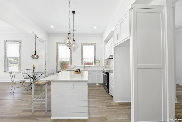 1526 Saint Marys, San Antonio, TX 78210 - kitchen featuring black / electric stove, healthy amount of natural light, a kitchen island, light wood finished floors, and crown molding