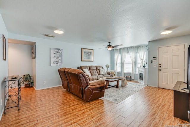 6459 Marlin Flts, San Antonio, TX 78244 - living room featuring light wood-style floors, ceiling fan, baseboards, and a textured ceiling