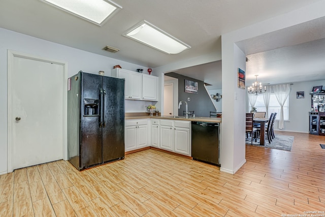 6459 Marlin Flts, San Antonio, TX 78244 - kitchen with black appliances, a sink, a chandelier, white cabinetry, and light wood finished floors