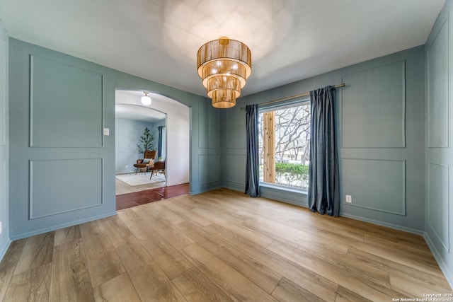 146 Canyon Oaks, Hollywood Park, TX 78232 - unfurnished room featuring arched walkways, a decorative wall, light wood finished floors, and a chandelier
