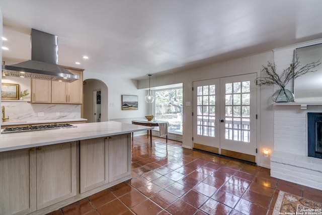 146 Canyon Oaks, Hollywood Park, TX 78232 - kitchen featuring island range hood, light brown cabinetry, stainless steel gas cooktop, arched walkways, and decorative backsplash