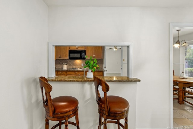 437 Spaceway, Windcrest, TX 78239 - kitchen featuring black microwave, brown cabinets, backsplash, light tile patterned floors, and stainless steel gas stovetop
