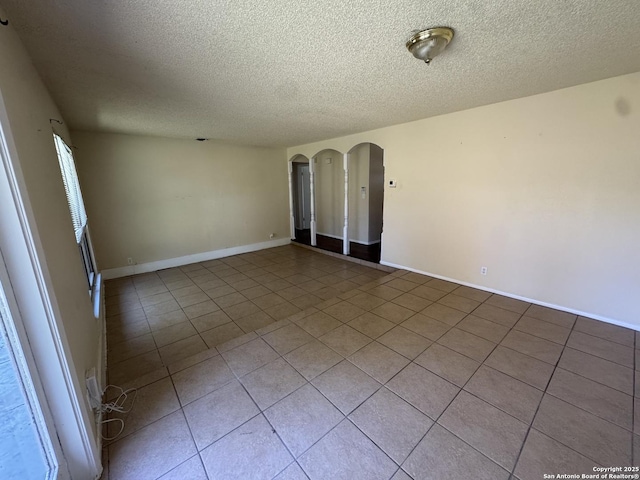 6917 Deep Lk, San Antonio, TX 78244 - unfurnished room with a textured ceiling, tile patterned floors, arched walkways, and baseboards