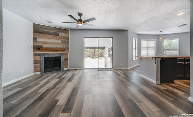 2310 Ruby Oaks, San Antonio, TX 78232 - unfurnished living room with a textured ceiling, ceiling fan, a premium fireplace, dark wood-type flooring, and baseboards