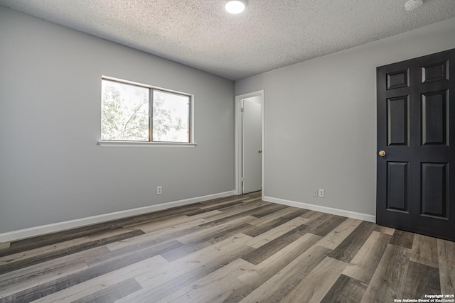 2310 Ruby Oaks, San Antonio, TX 78232 - unfurnished bedroom with a textured ceiling, wood finished floors, and baseboards