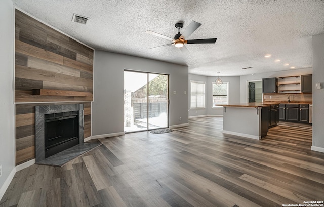 2310 Ruby Oaks, San Antonio, TX 78232 - unfurnished living room featuring a ceiling fan, a textured ceiling, a high end fireplace, baseboards, and dark wood-style floors