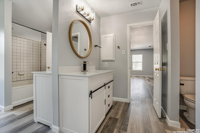 2310 Ruby Oaks, San Antonio, TX 78232 - full bathroom with a textured ceiling, vanity, wood finished floors, toilet, and bathing tub / shower combination