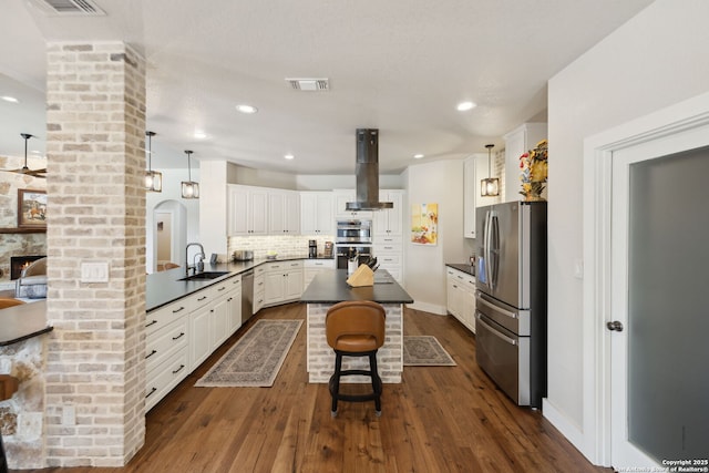 2803 River Way, Spring Branch, TX 78070 - kitchen featuring appliances with stainless steel finishes, range hood, dark countertops, a kitchen island, and a breakfast bar area