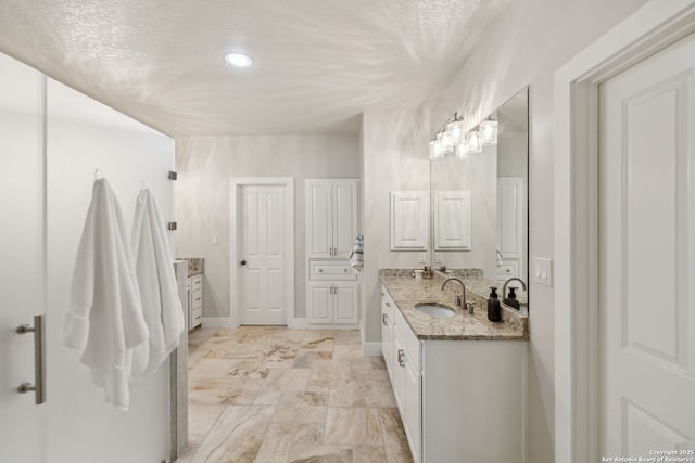 2803 River Way, Spring Branch, TX 78070 - full bath with two vanities, recessed lighting, marble finish flooring, a textured ceiling, and baseboards