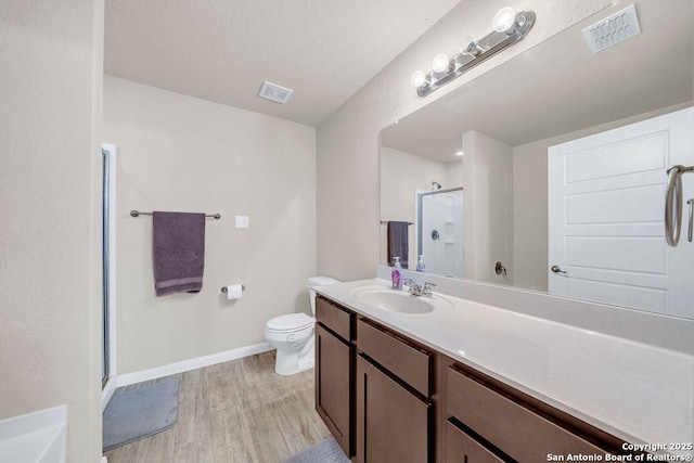 2015 Sisyphus, San Antonio, TX 78245 - full bath with a stall shower, toilet, vanity, baseboards, and wood finished floors
