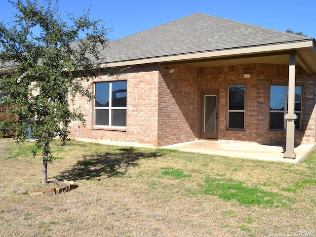 12118 Fort Leaton, San Antonio, TX 78254 - back of property with brick siding, a patio area, a lawn, and a shingled roof