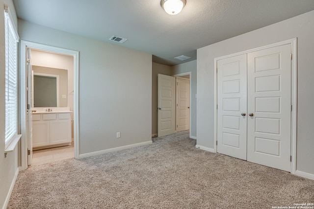 10206 Daylily, Boerne, TX 78006 - unfurnished bedroom featuring light carpet, a closet, baseboards, and connected bathroom