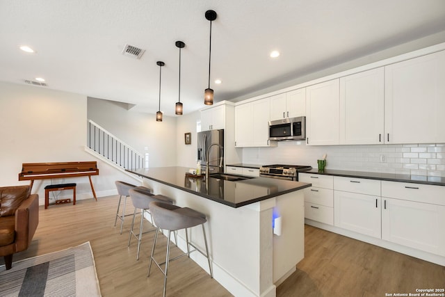 1618 W Lawndale Unit, San Antonio, TX 78209 - kitchen with appliances with stainless steel finishes, dark countertops, a sink, light wood finished floors, and backsplash