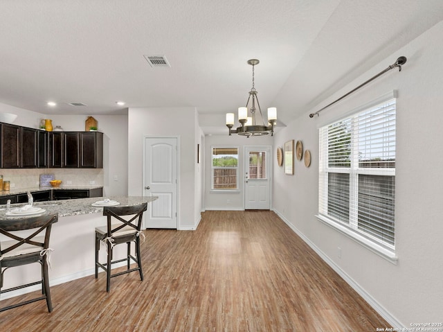 412 Town Frk, Cibolo, TX 78108 - kitchen with a breakfast bar, a chandelier, light wood-style floors, tasteful backsplash, and decorative light fixtures