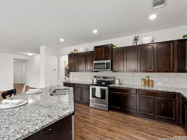 412 Town Frk, Cibolo, TX 78108 - kitchen featuring appliances with stainless steel finishes, a sink, dark brown cabinets, backsplash, and light stone counters