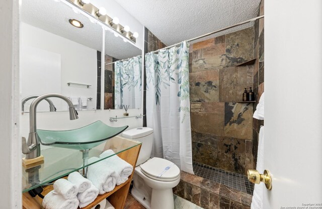 16414 Spruce Cove St, San Antonio, TX 78247 - full bathroom with toilet, a tile shower, vanity, and a textured ceiling
